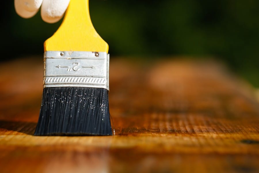 paintbrush sliding over wooden surface, protecting wood